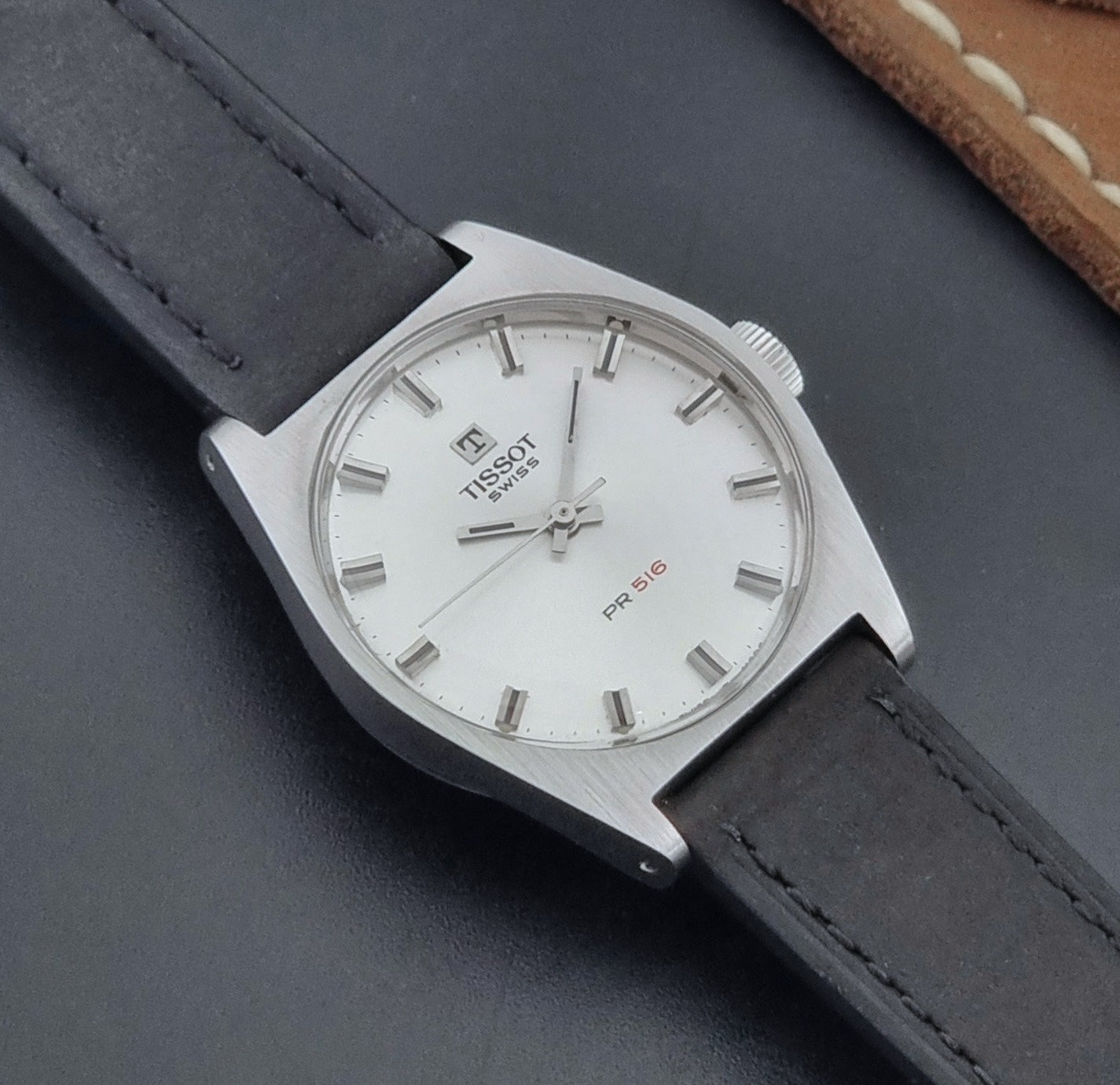 Vintage Tissot Wristwatch 41620 PR 516 with black leather strap on a grey surface close  up dial view