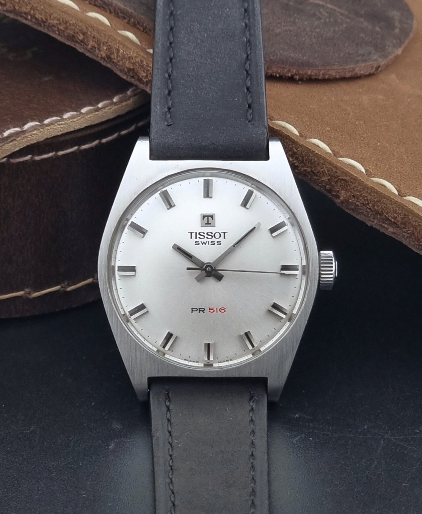 Vintage Tissot Wristwatch 41620 PR 516 with black leather strap on a grey surface dial view