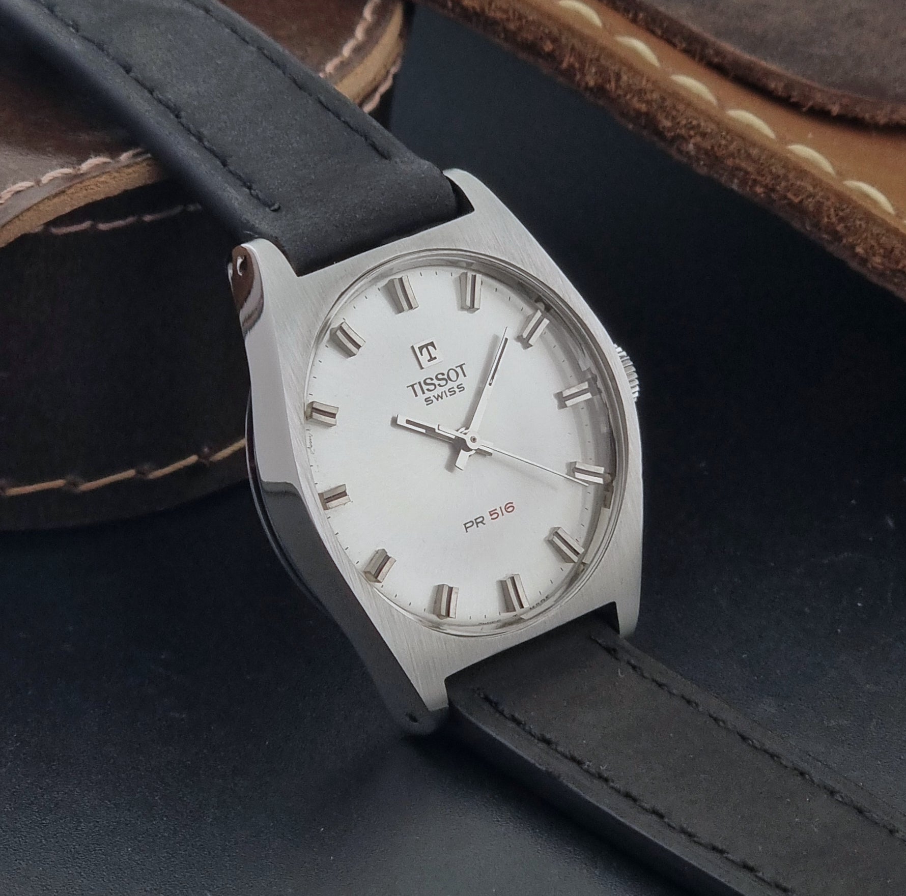Vintage Tissot Wristwatch 41620 PR 516 with black leather strap on a grey surface side view