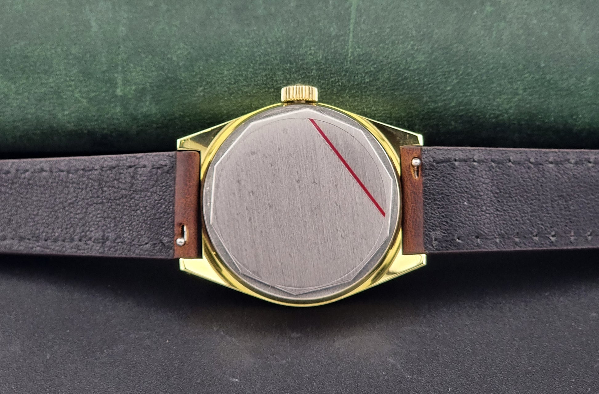 Vintage Tissot Watch 41620 PR 516 in Gold with brown leather strap on a green background case back view