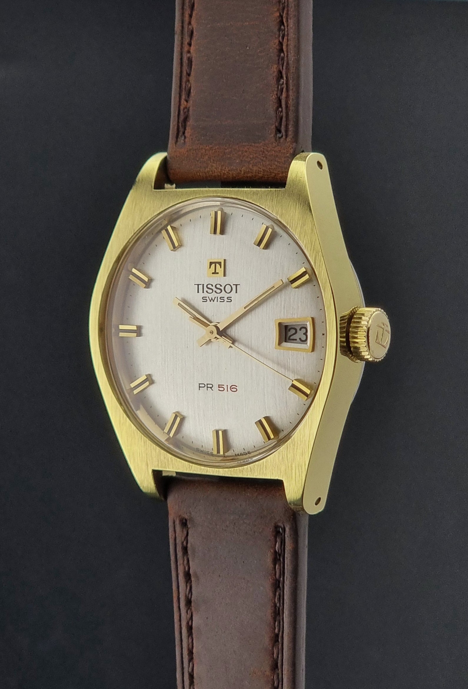 Vintage Tissot Watch 41620 PR 516 in Gold with brown leather strap on a green background crown profile view