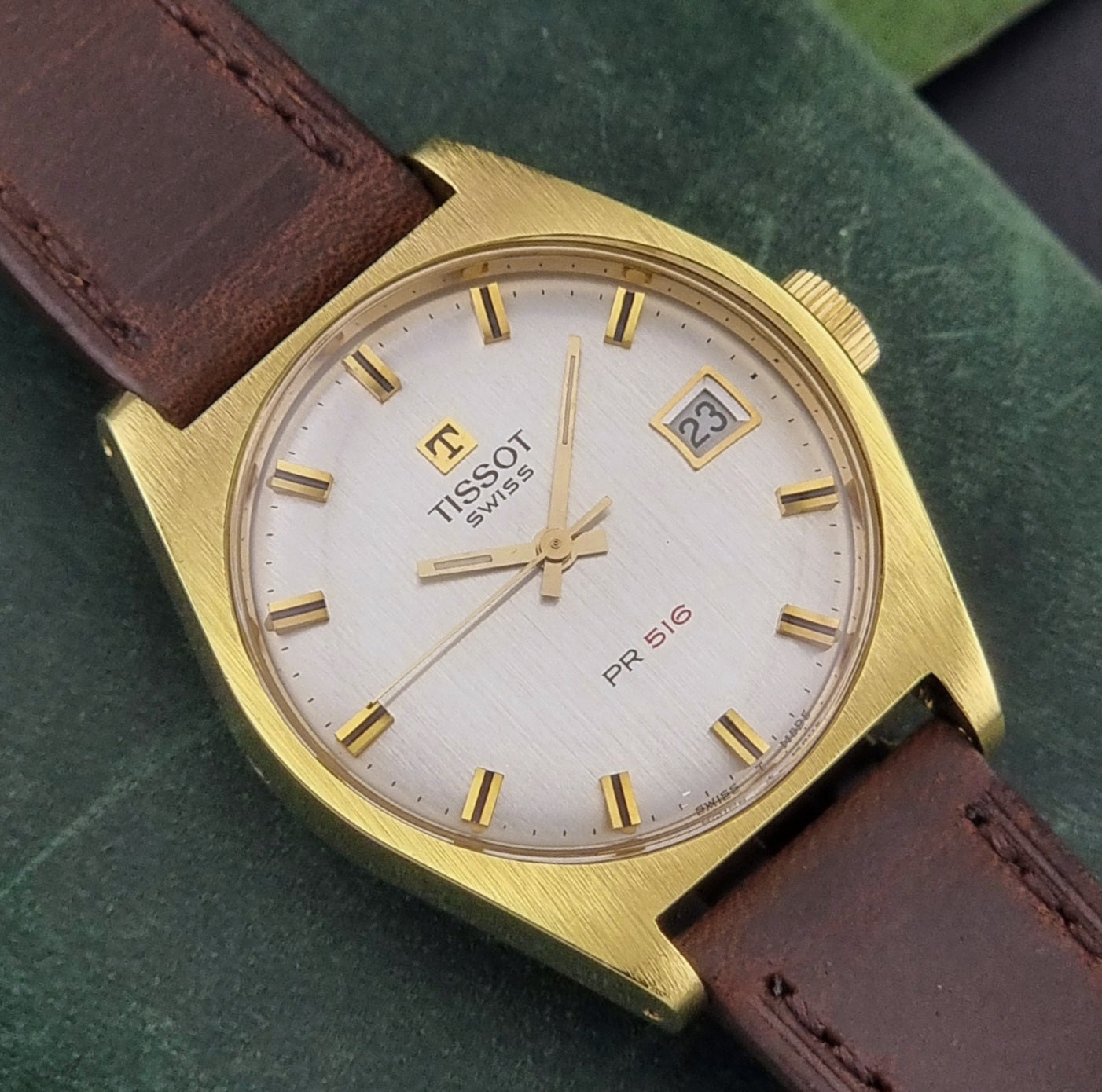 Vintage Tissot Watch 41620 PR 516 in Gold with brown leather strap on a green background front