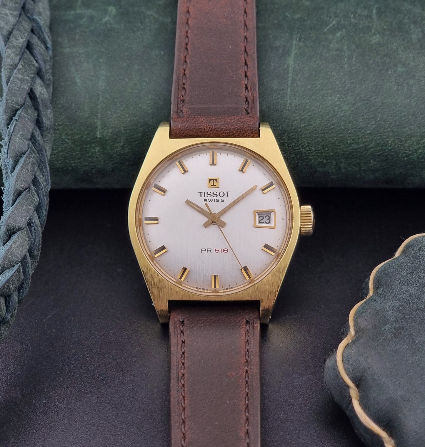 Vintage Tissot Watch 41620 PR 516 in Gold with brown leather strap on a green background front view