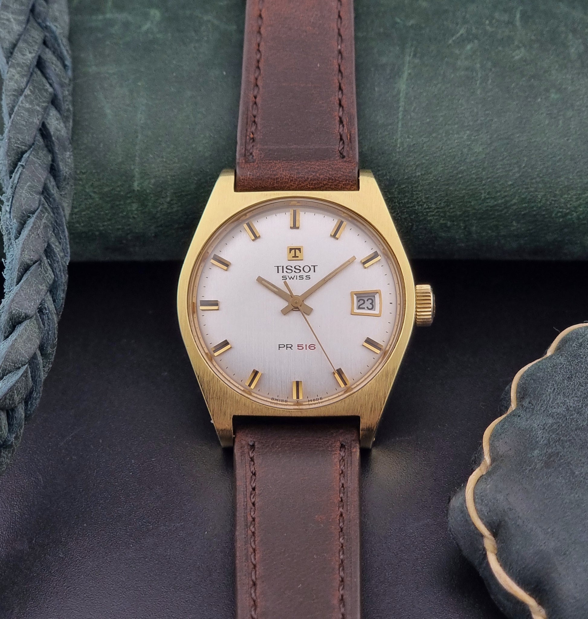 Vintage Tissot Watch 41620 PR 516 in Gold with brown leather strap on a green background front view