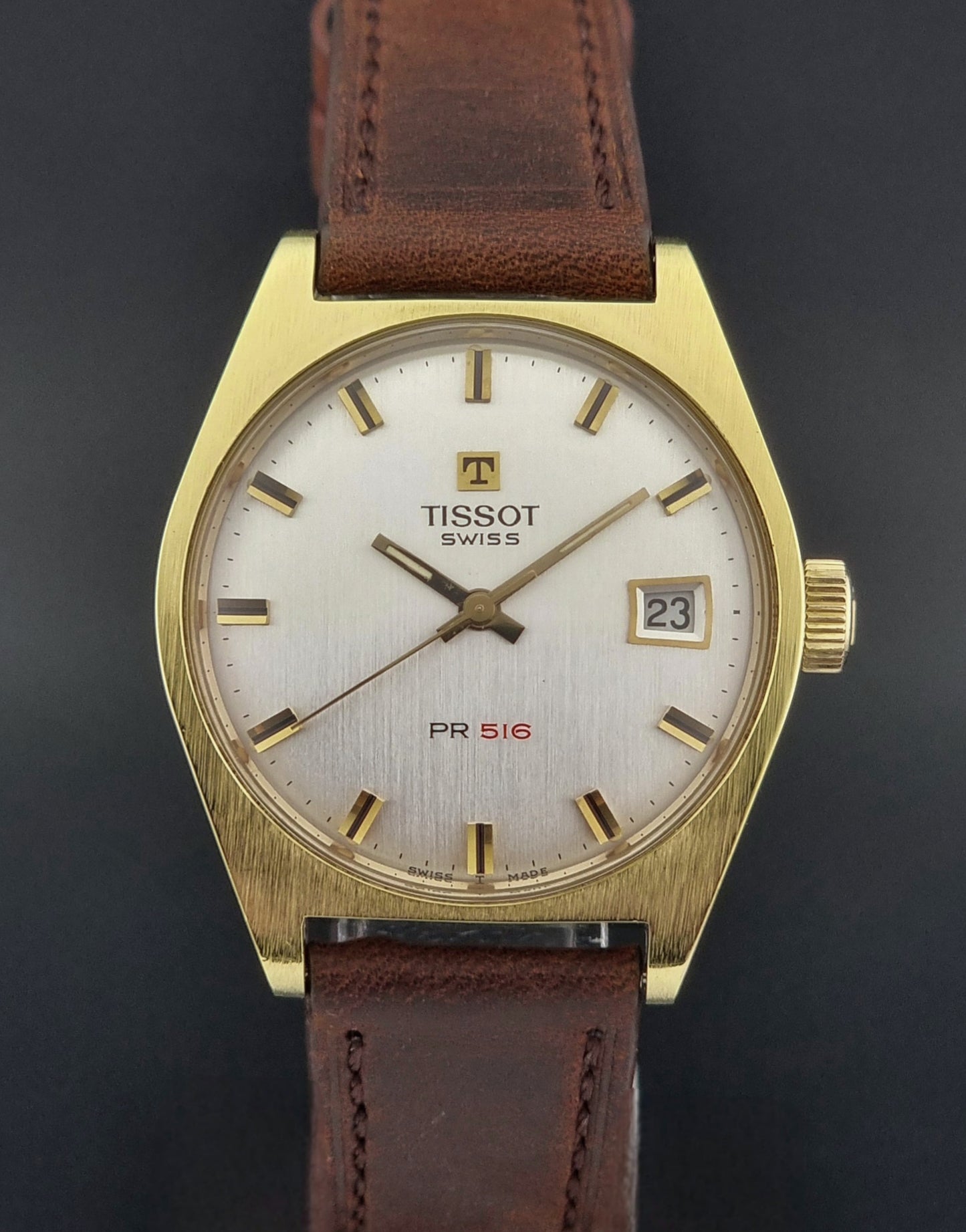 Vintage Tissot Watch 41620 PR 516 in Gold with brown leather strap on a green background close front view