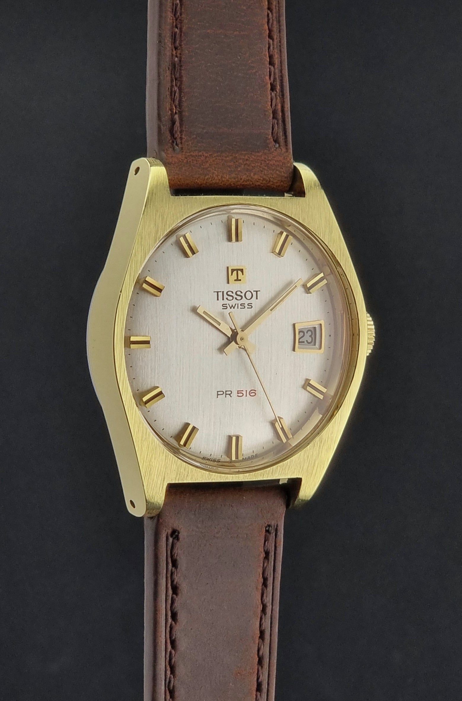 Vintage Tissot Watch 41620 PR 516 in Gold with brown leather strap on a green background side profile viiew