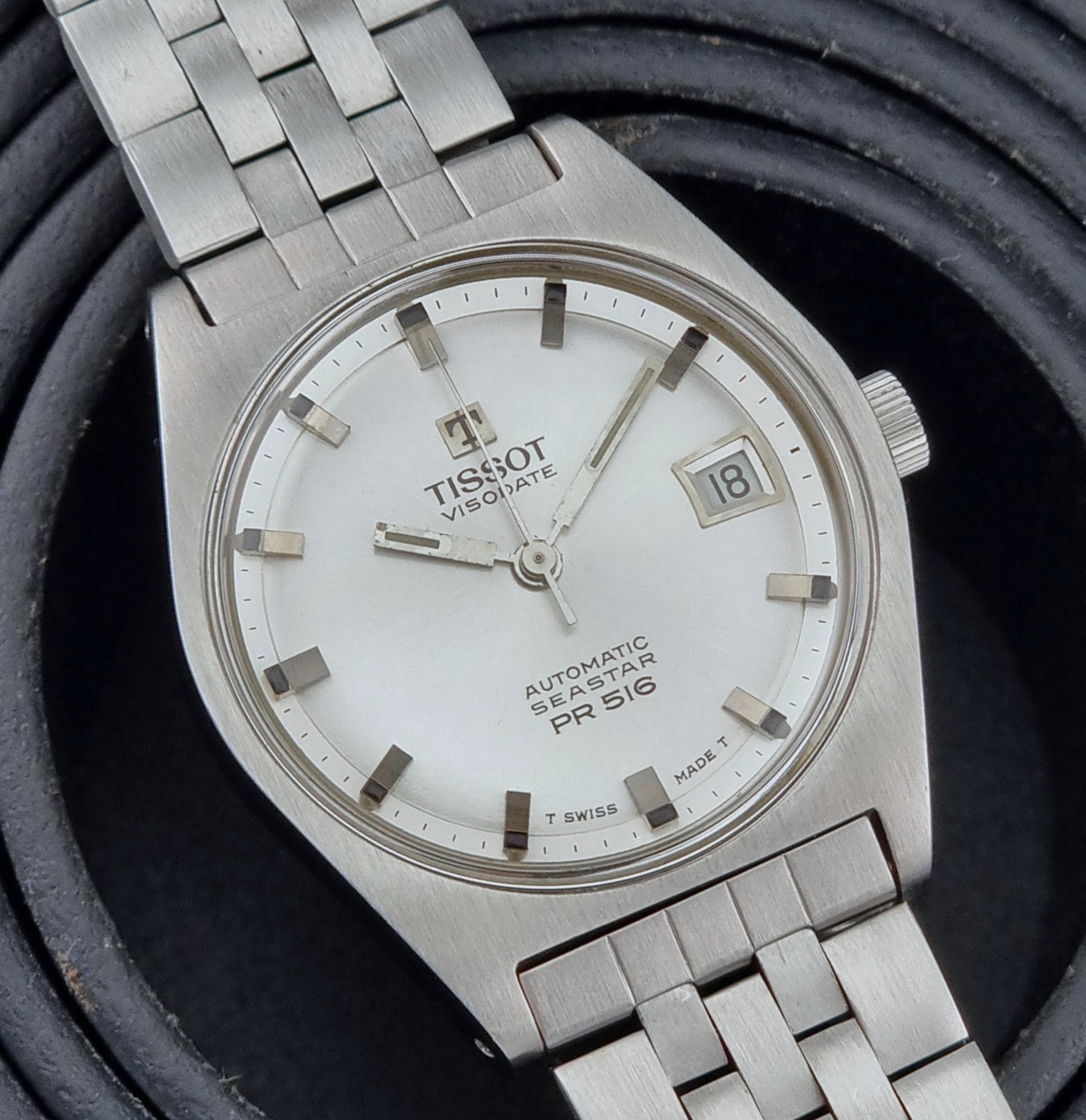 Tissot Seastar Visodate watch with white face on a dark textured background
