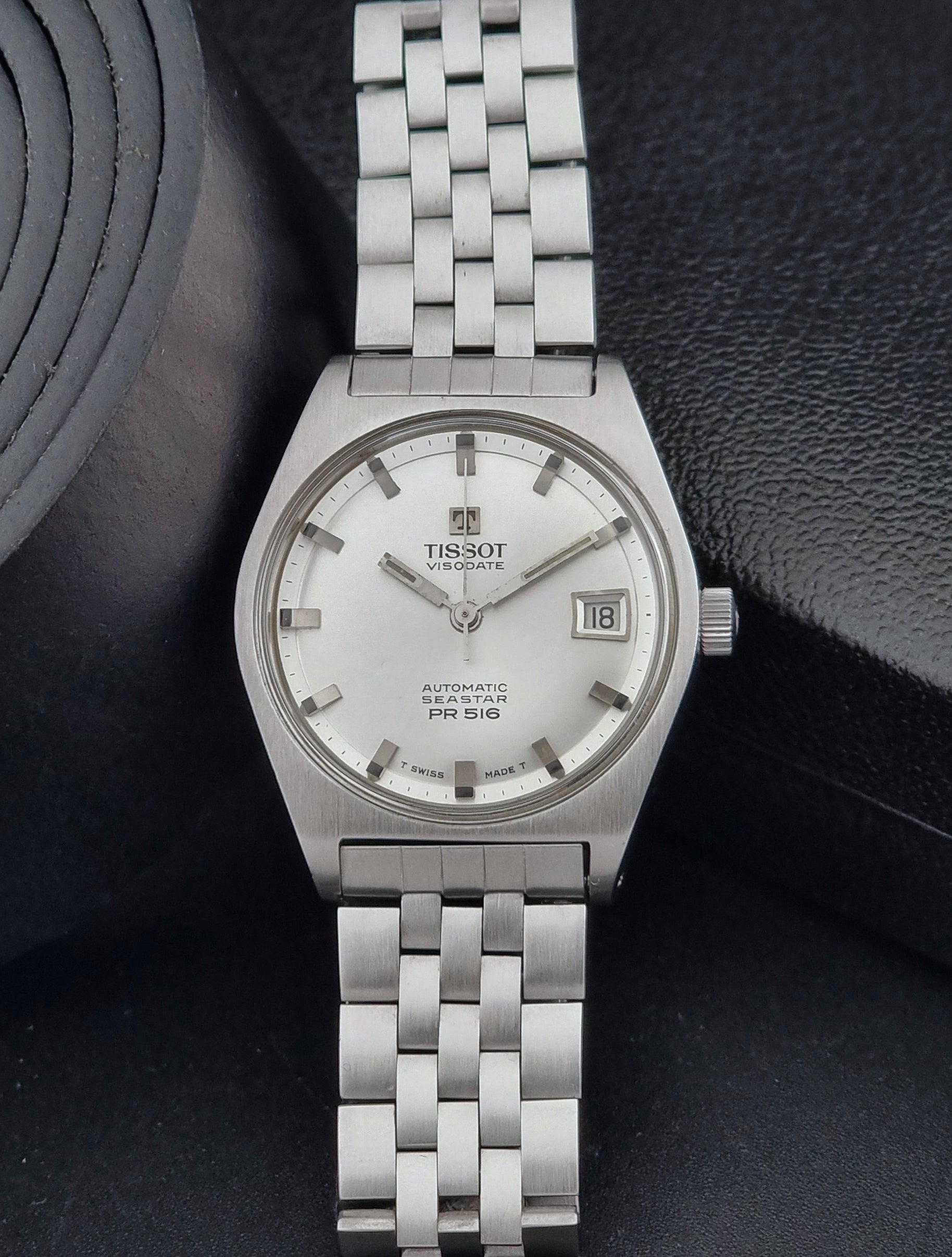 Tissot Seastar Visodate watch with a white face on a dark textured background
