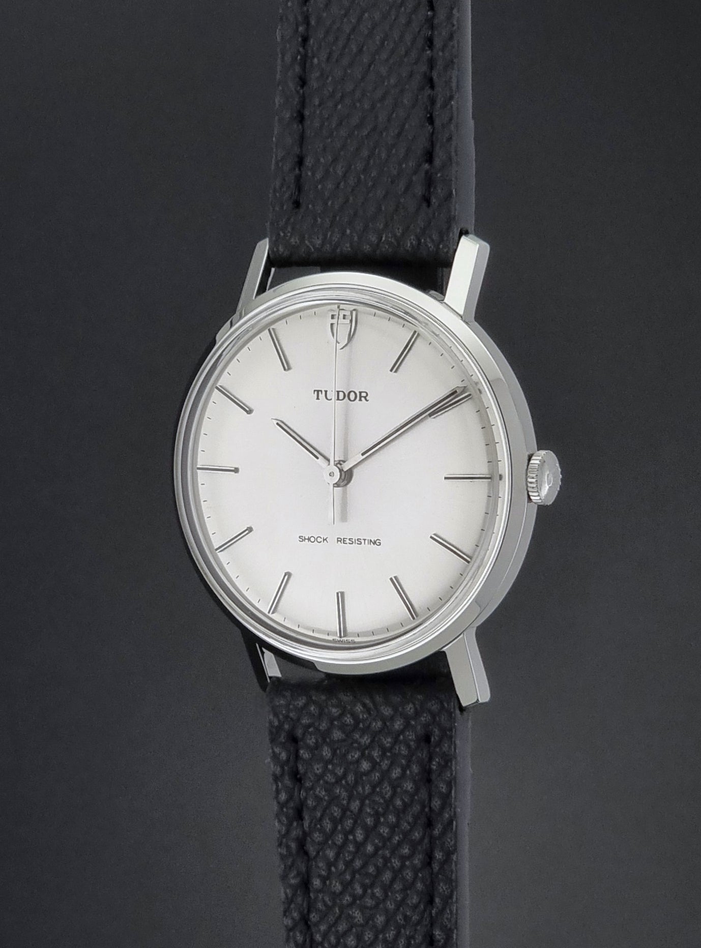 Vintage Tudor 9800 watch with black leather strap on a dark gray background crown profile view
