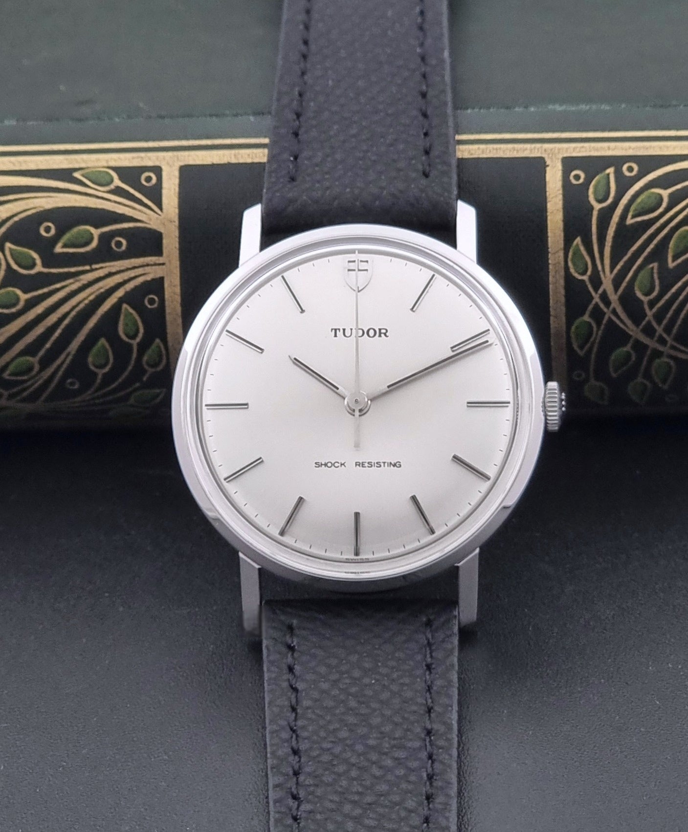 Vintage Tudor 9800 watch with black leather strap on a dark gray background dial view