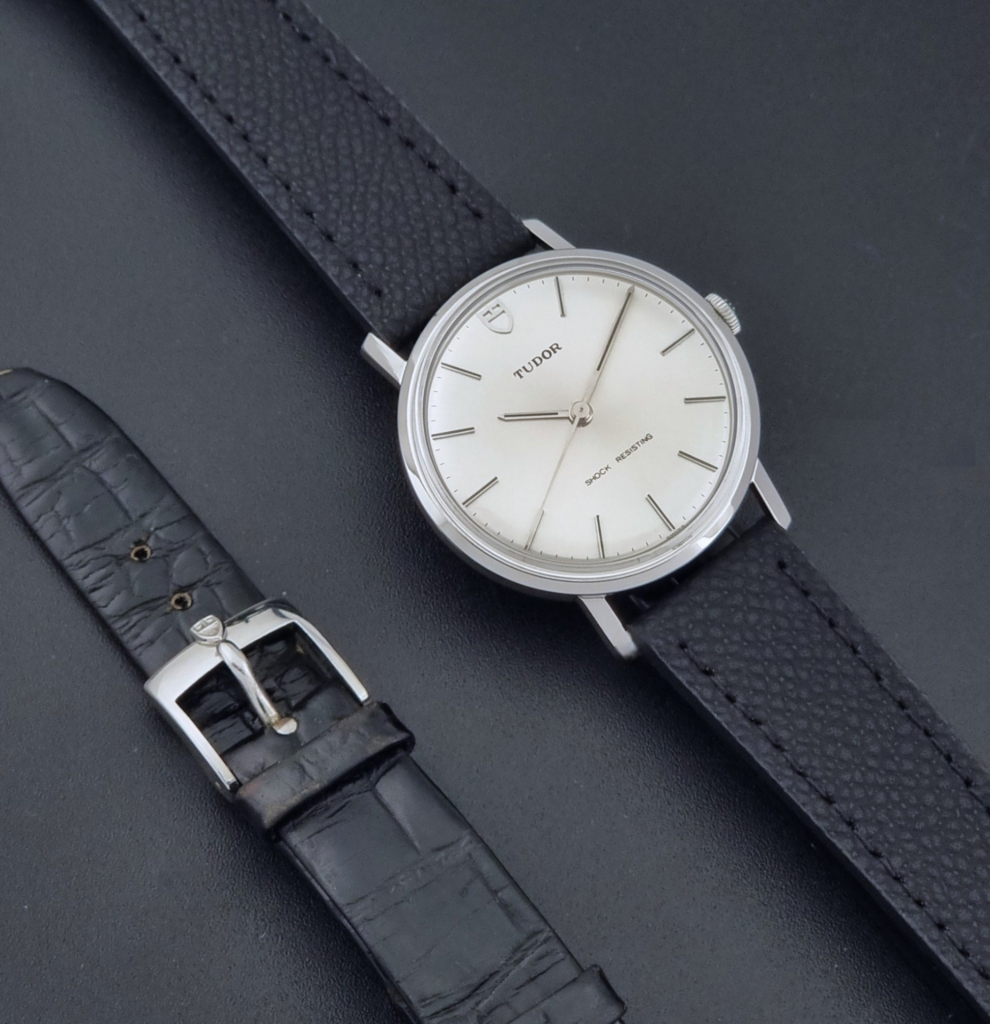 Vintage Tudor 9800 watch with black leather strap on a dark gray background dial