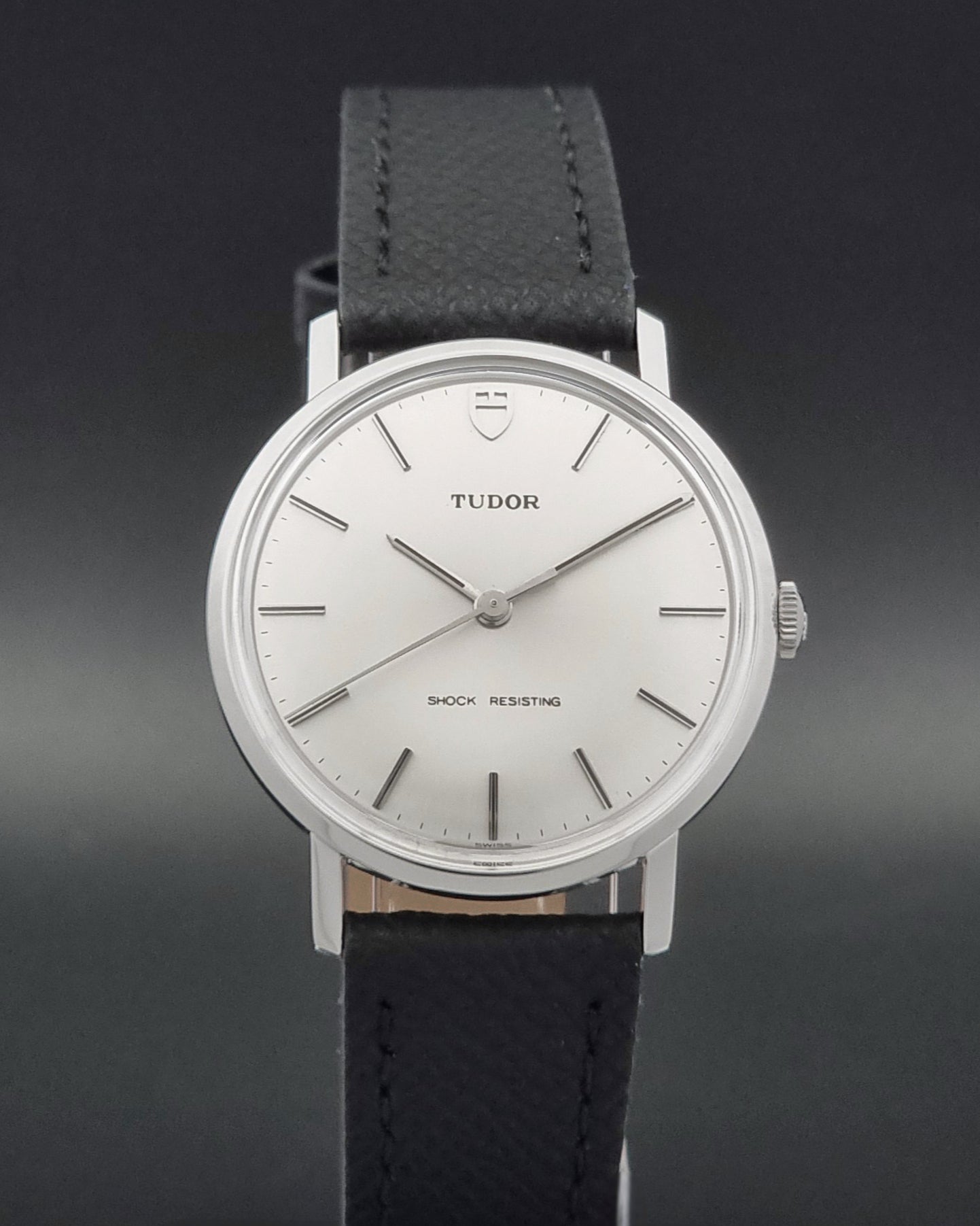 Vintage Tudor 9800 watch with black leather strap on a dark gray background close dial view