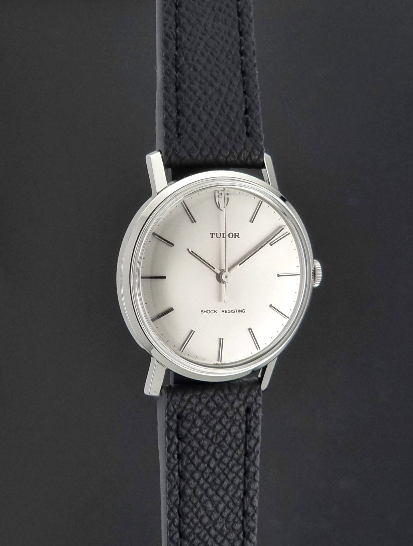 Vintage Tudor 9800 watch with black leather strap on a dark gray background side profile view