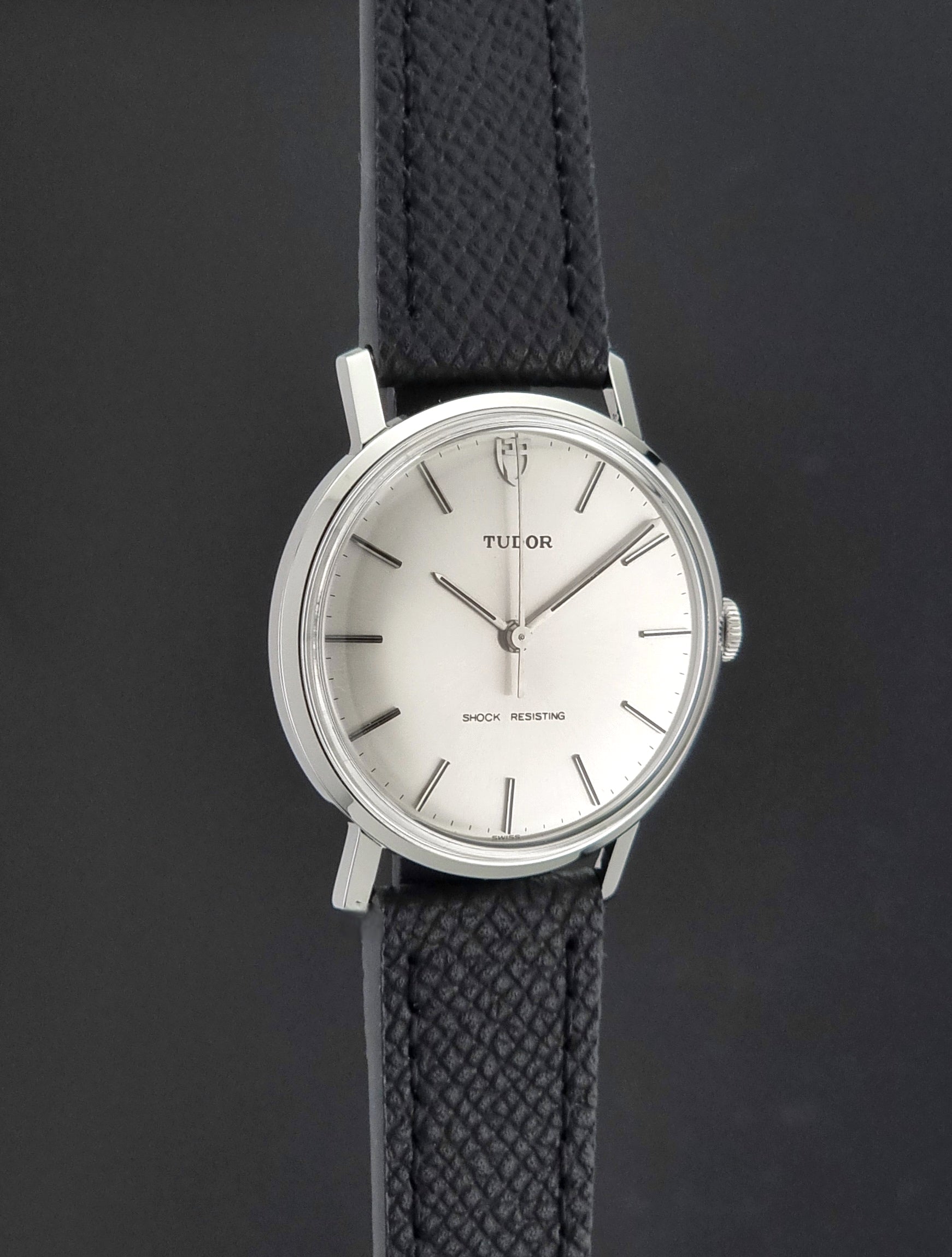 Vintage Tudor 9800 watch with black leather strap on a dark gray background side profile view