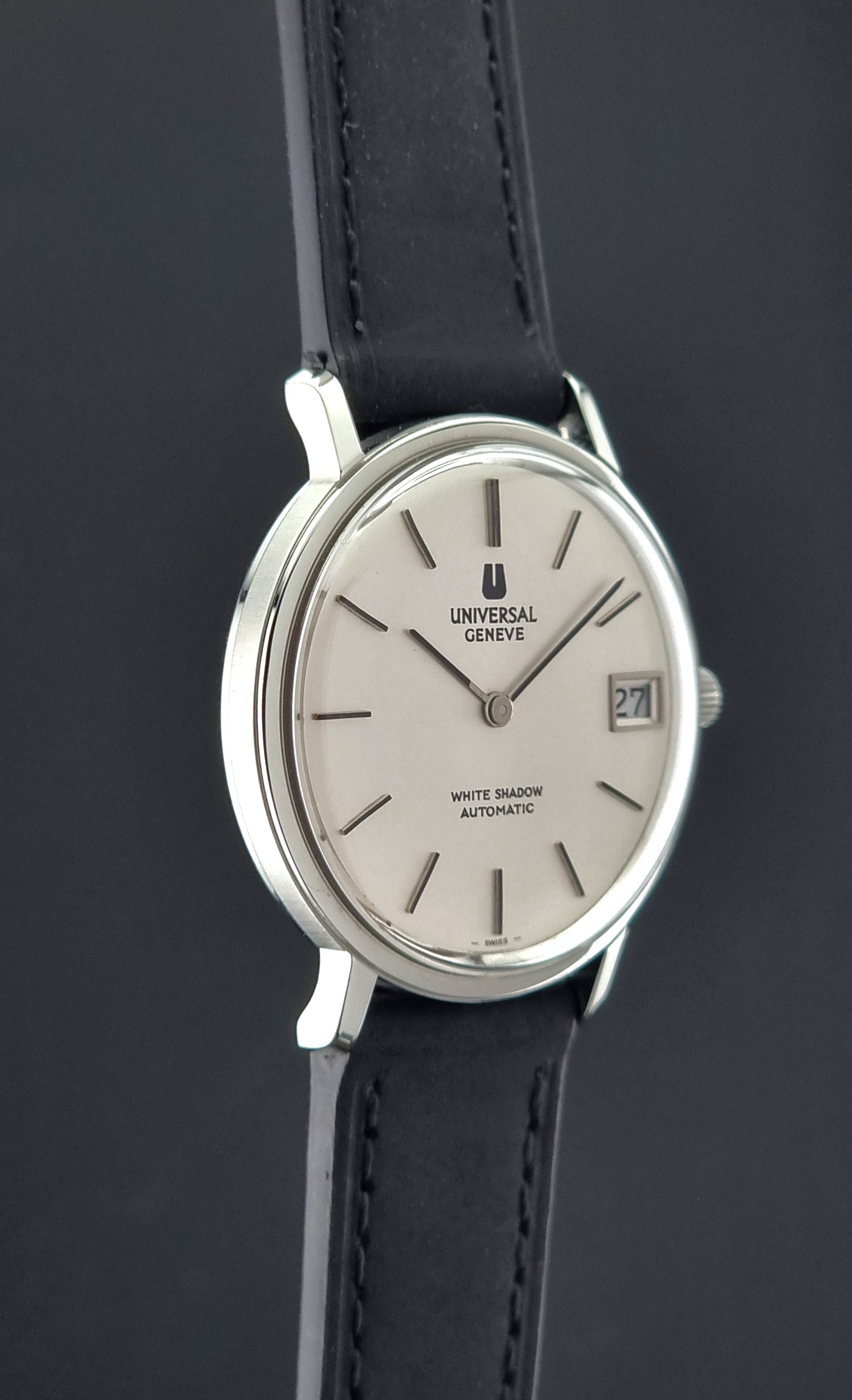 Wristwatch Universal Geneve with black leather strap and silver case on a dark background