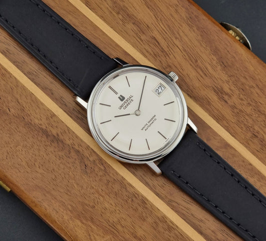 Universal Geneve Watch with black strap on a wooden surface