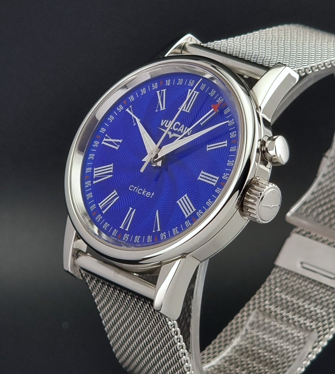 Vulcain Cricket Alarm watch 100102.008 with a blue face on a dark gray background crown view