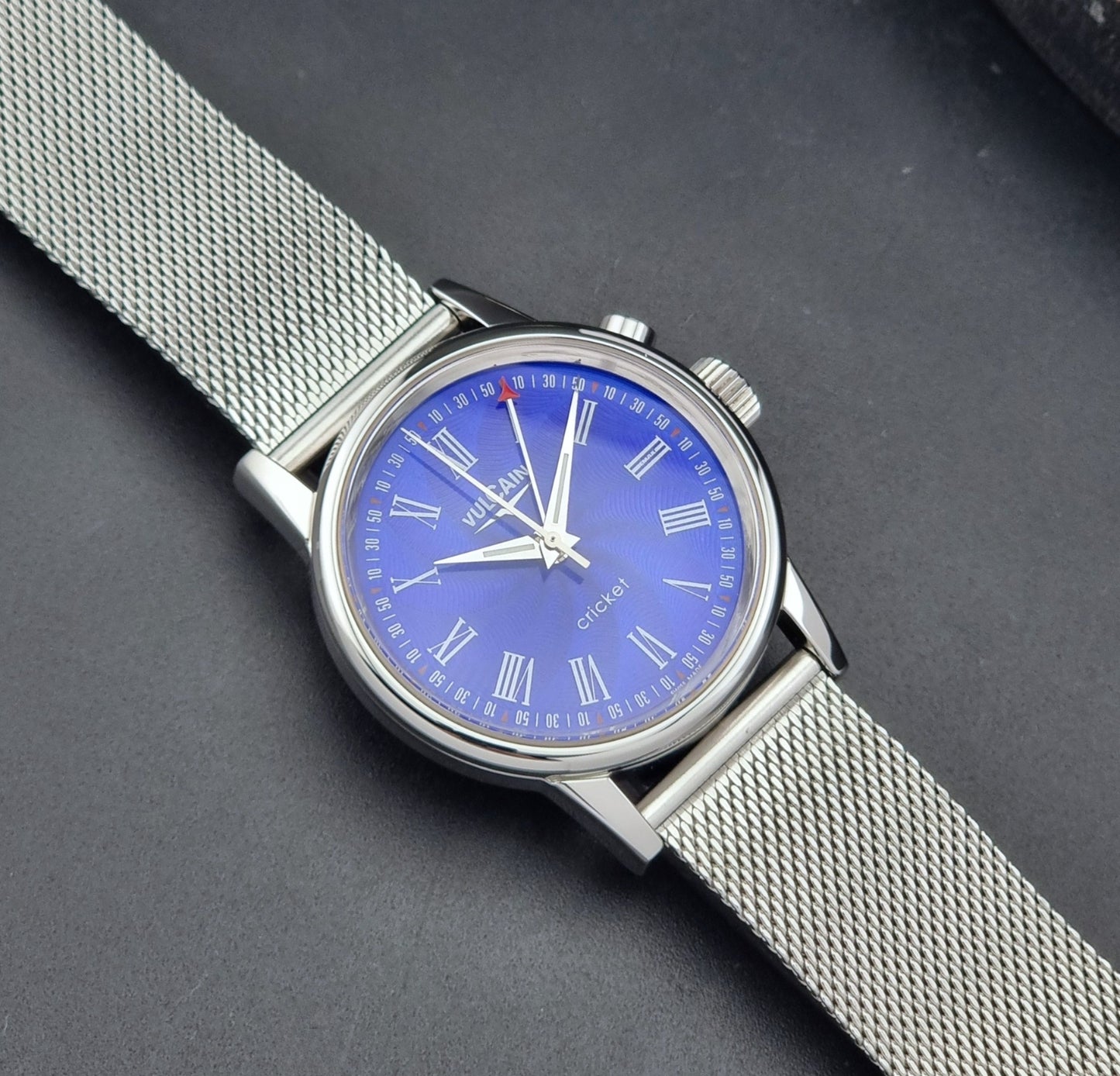 Vulcain Cricket Alarm watch 100102.008 with a blue face on a dark gray background dial