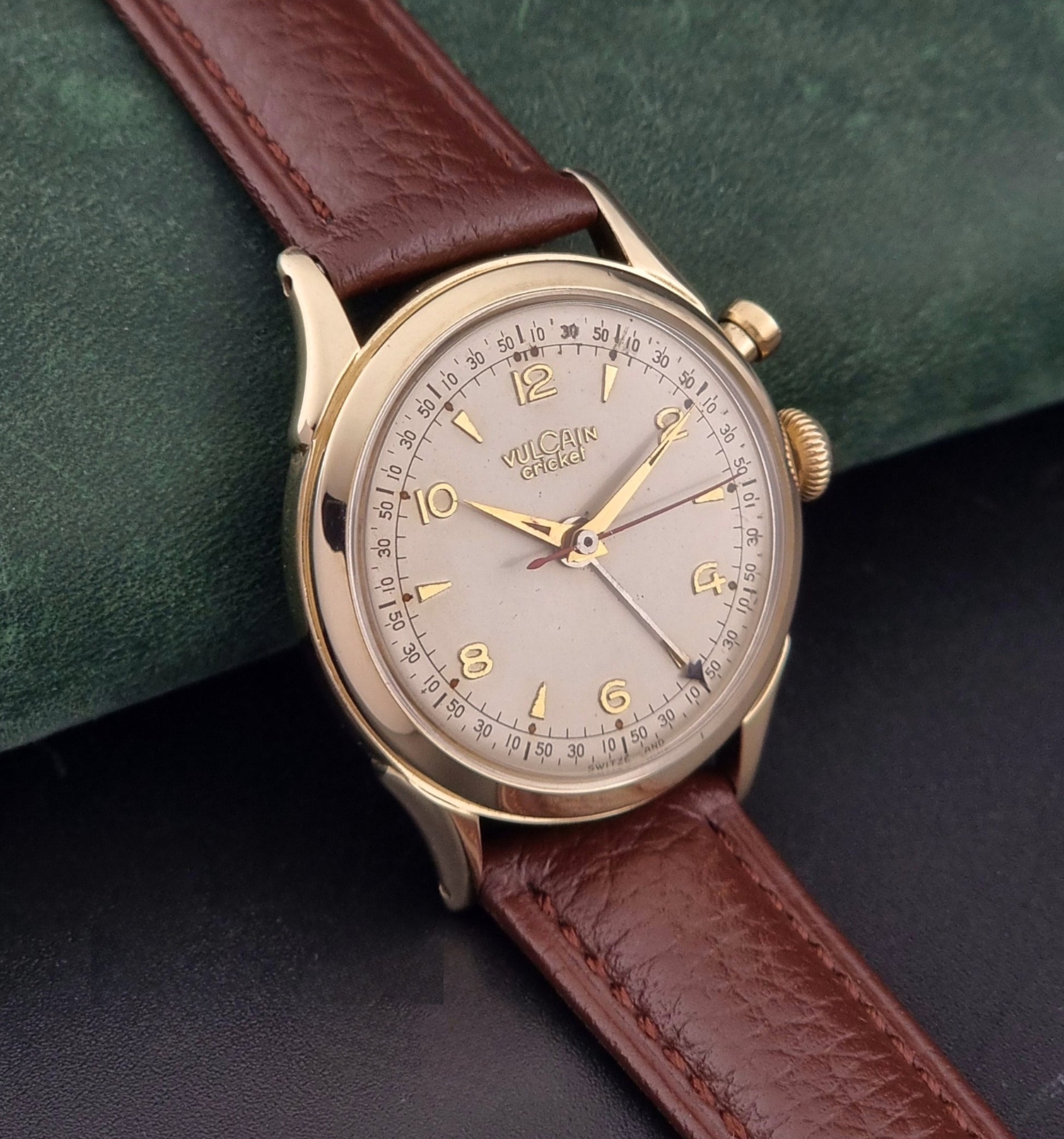Vulcain cricket W197446 Watch with brown leather strap and gold case on a dark green background