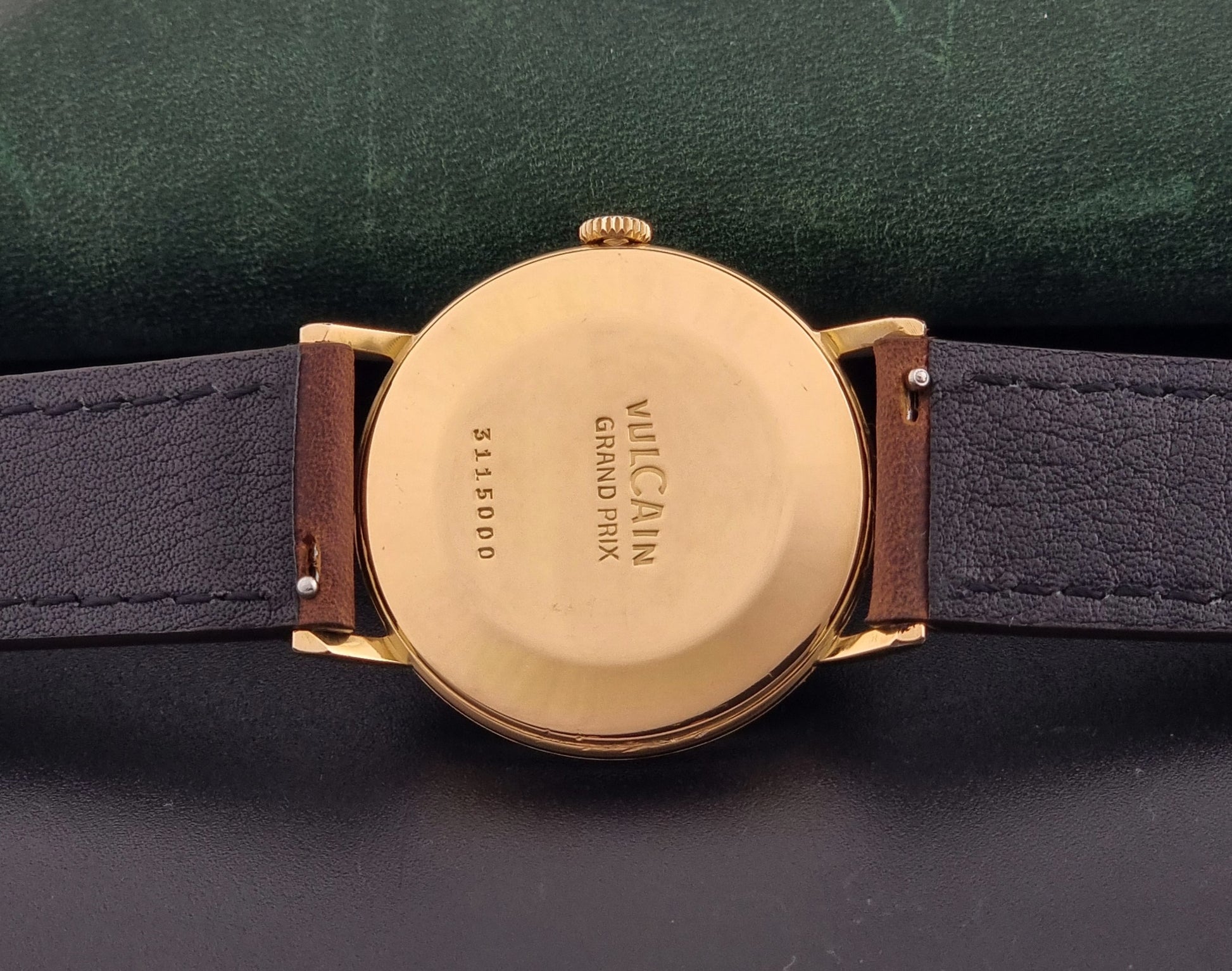 Vintage Vulcain Grand Prix watch with brown leather strap and gold case on a dark surface case back view