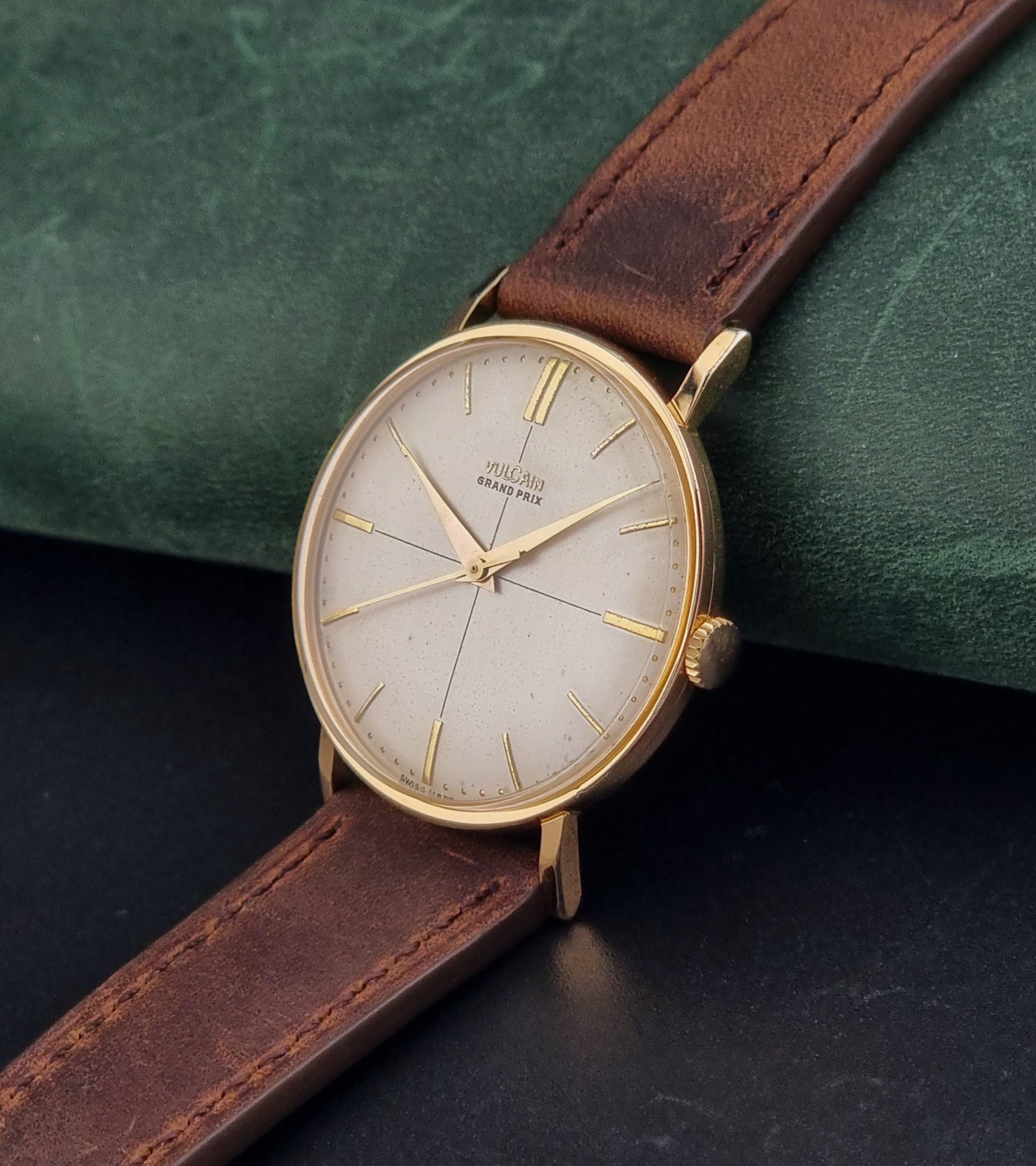 Vintage Vulcain Grand Prix watch with brown leather strap and gold case on a dark surface crown view