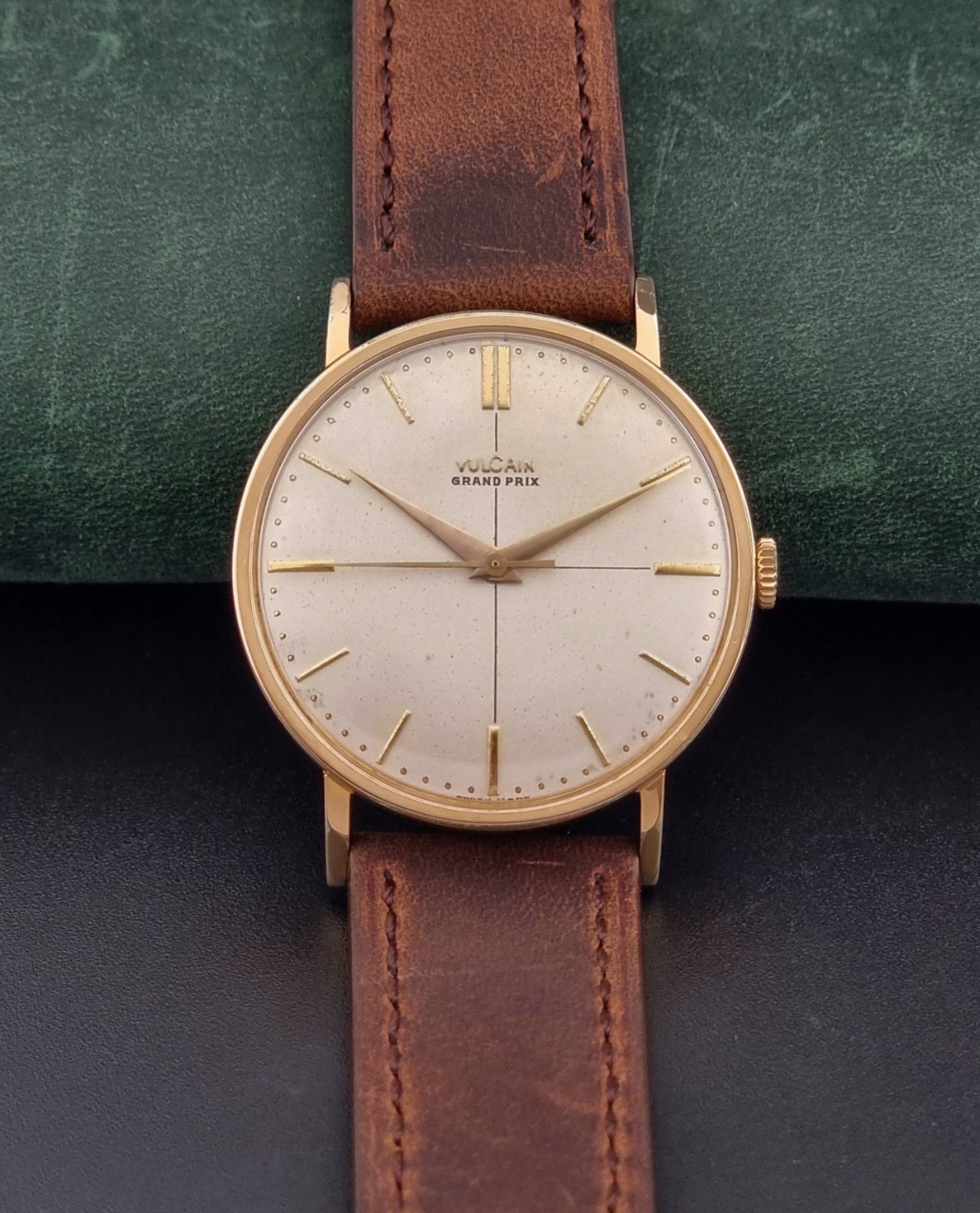 Vintage Vulcain Grand Prix watch with brown leather strap and gold case on a dark surface dial view