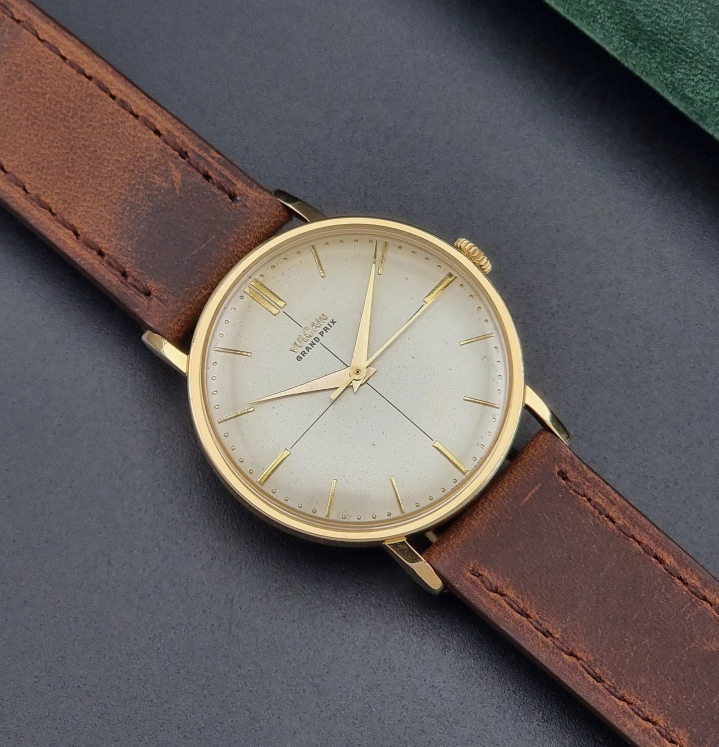 Vintage Vulcain Grand Prix watch with brown leather strap and gold case on a dark surface close up dial view