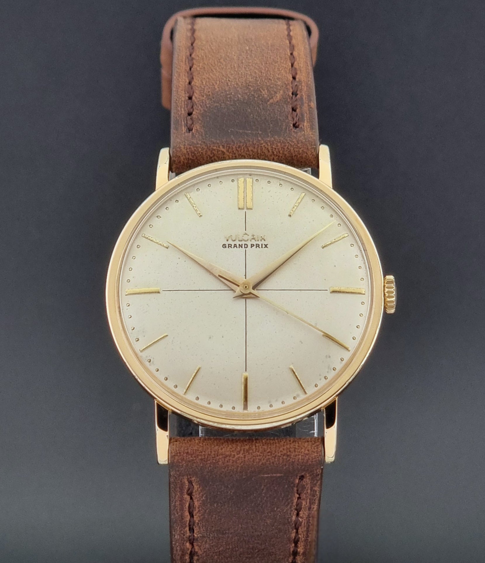 Vintage Vulcain Grand Prix watch with brown leather strap and gold case on a dark surface close dial view