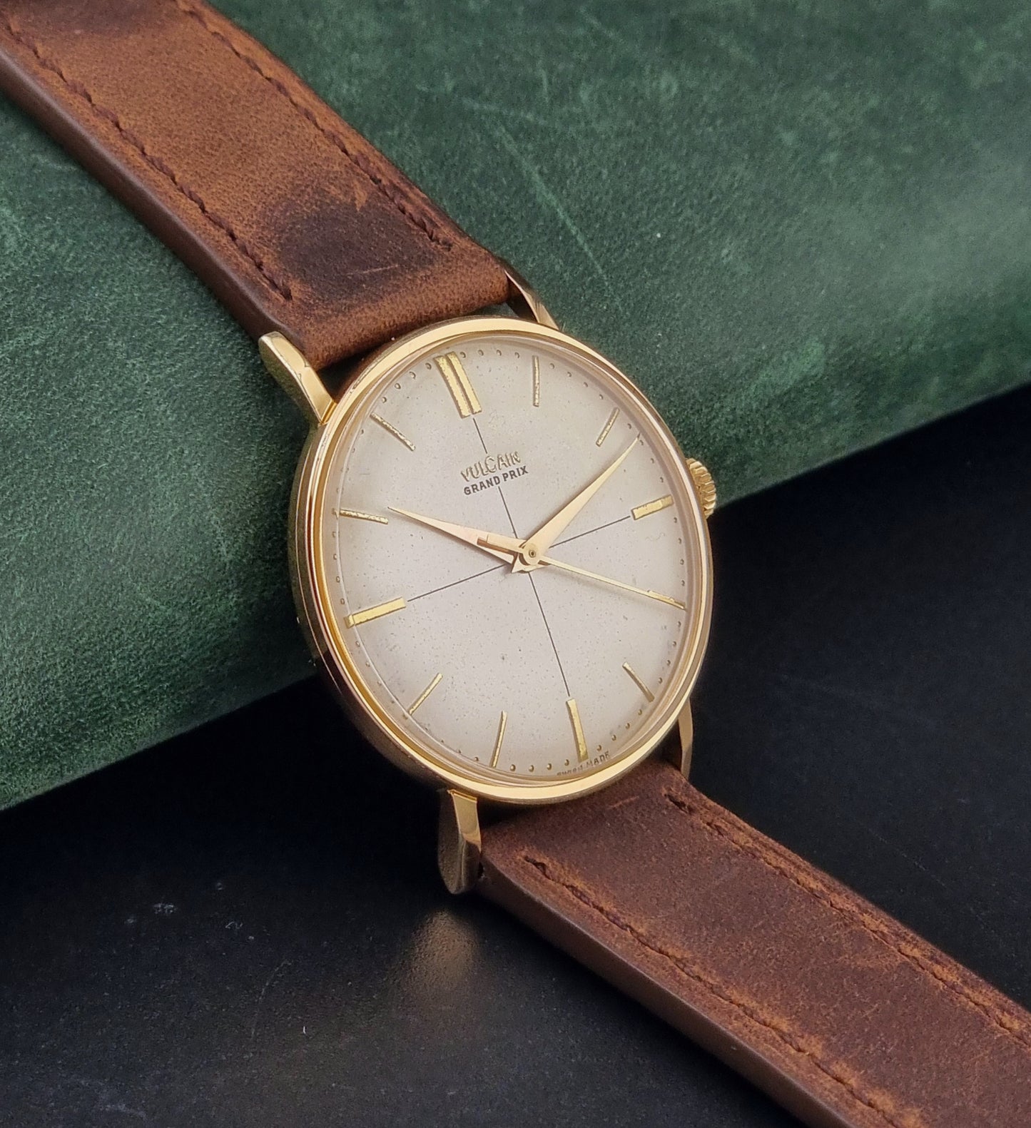 Vintage Vulcain Grand Prix watch with brown leather strap and gold case on a dark surface side view