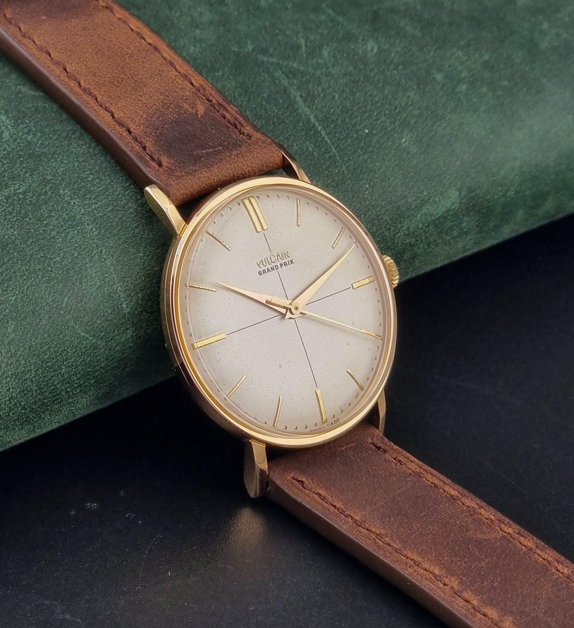 Vintage Vulcain Grand Prix watch with brown leather strap and gold case on a dark surface side view