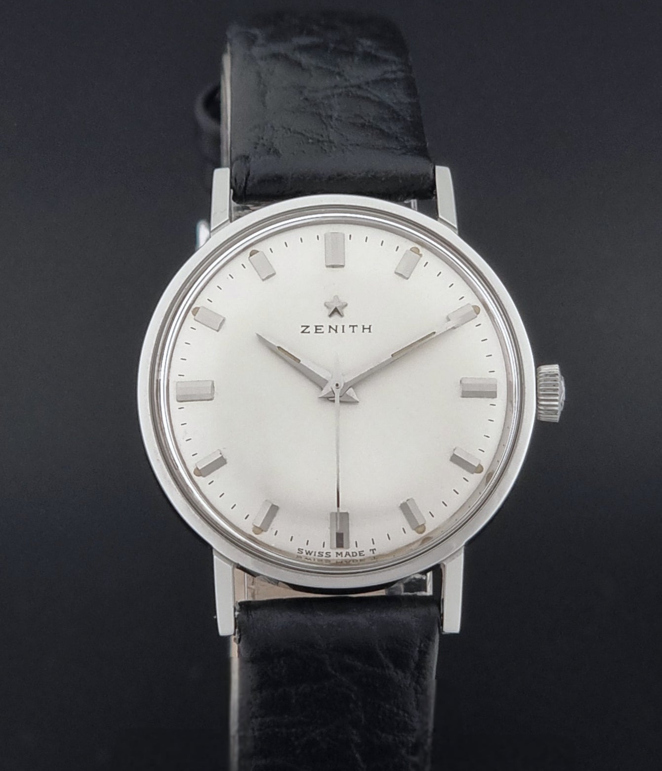 Vintage Unisex Zenith Wristwatch Manual wind with a black strap on a dark background close dial view