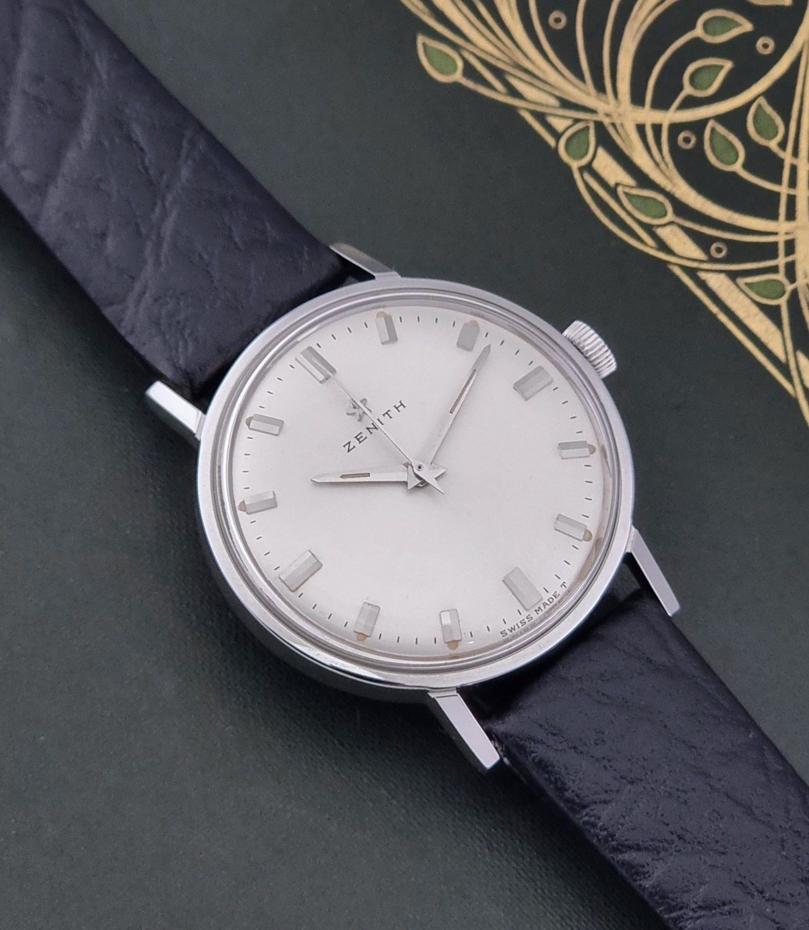 Vintage Unisex Zenith Wristwatch Manual wind with a black strap on a dark background close up dial view