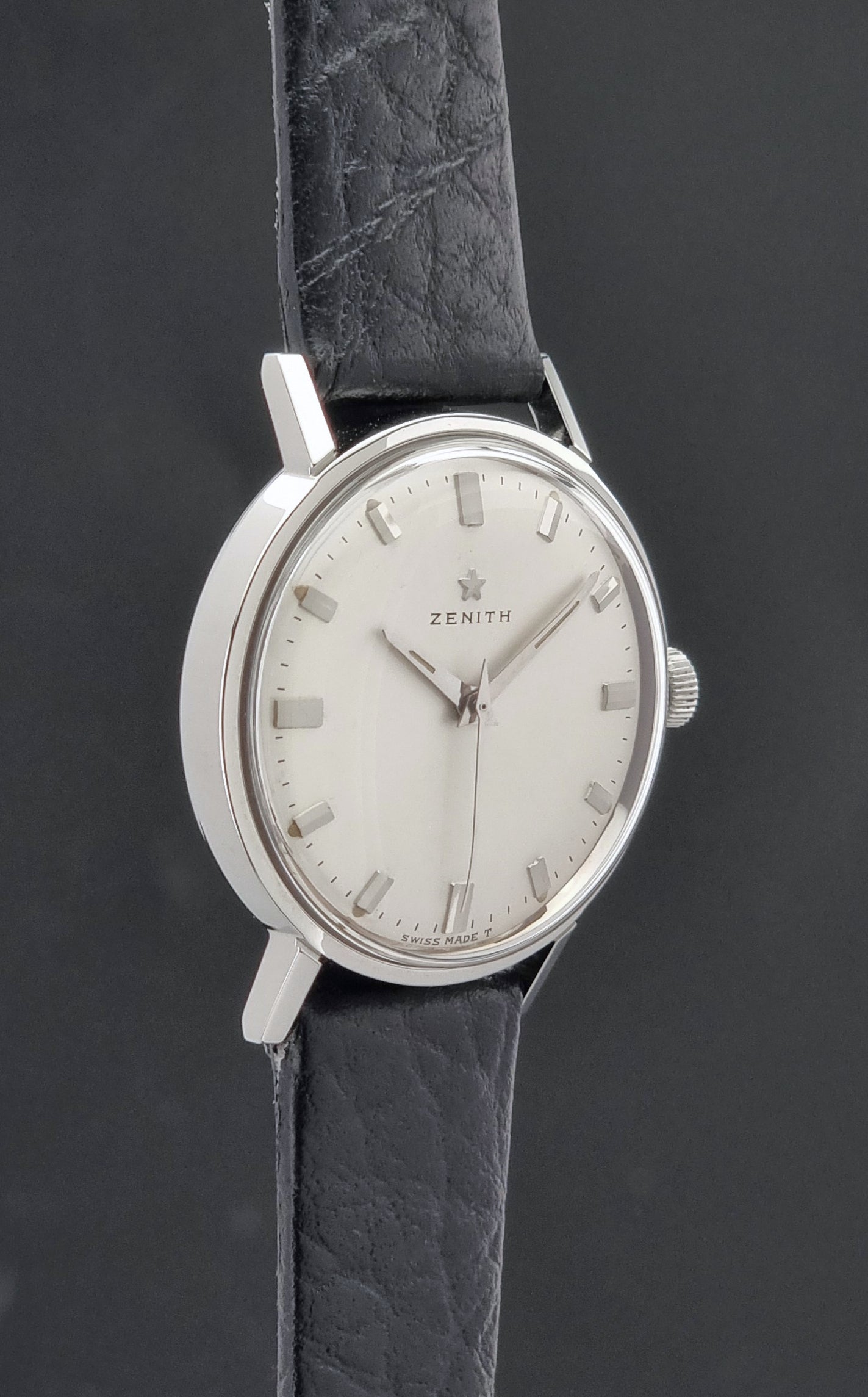 Vintage Unisex Zenith Wristwatch Manual wind with a black strap on a dark background side profile view